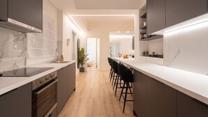 A modern kitchen with a central island, dark cabinetry, and a marble backsplash. - Exclusive and Deluxe Apartment in Athens (Athens)
