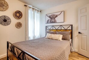 A bedroom with a bed, a headboard, a door, and wall decorations.