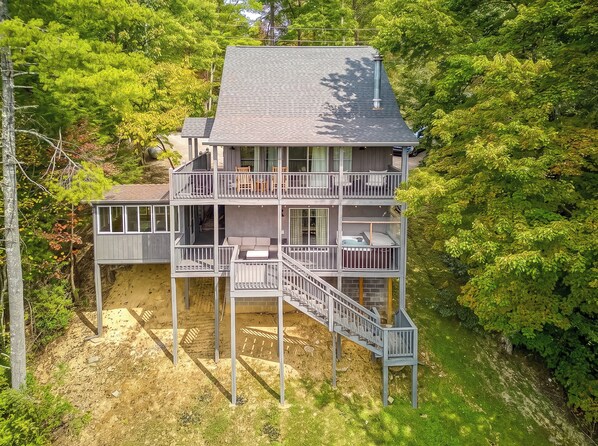 Une maison en bois à plusieurs niveaux, dotée de balcons, située dans une zone boisée.