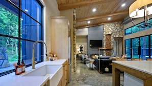 Una cocina moderna con un ventanal grande, armarios de madera y una pared decorativa de piedra.