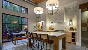 Una cocina moderna con una isla grande, taburetes de bar e iluminación colgante.