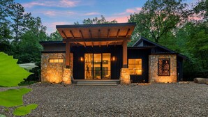 Una casa moderna con fachada de piedra, puertas de vidrio grandes y un porche de madera.