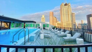 Uma área de piscina no terraço, com espreguiçadeiras e um horizonte urbano ao fundo.