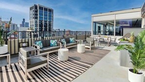 Terraço no telhado com área de estar externa moderna, incluindo sofás e cadeiras, e um espaço para refeições.