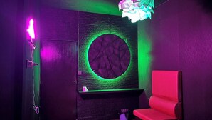A room with a circular wall feature, a red chair, and a hanging light fixture. - Doctor Alien Hostel (Bangkok)