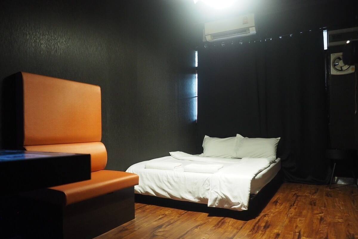 A room with a bed, a chair, and an air conditioning unit.