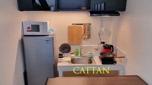 A compact kitchen with a wooden table, a built-in microwave, and a TV mounted above the counter. - Cozy Condo: Clean, 24/7 Security, 
Near S&R Davao and some Universities/Schools (Davao City)