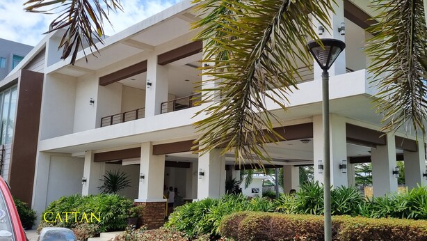 A modern two-story building with a covered entrance and a landscaped garden. - Cozy Condo: Clean, 24/7 Security, 
Near S&R Davao and some Universities/Schools (Davao City)
