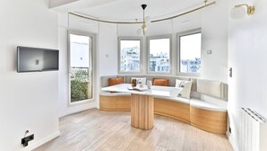 Un interior moderno con una zona de estar curvada, ventanas amplias y un televisor de pantalla plana.