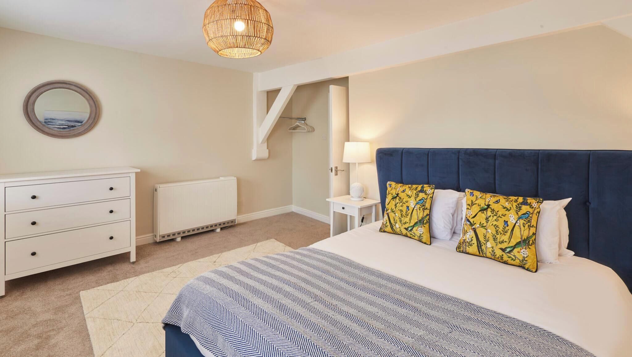 A bedroom with a bed, a dresser, a radiator, a lamp, and a hanging light fixture.