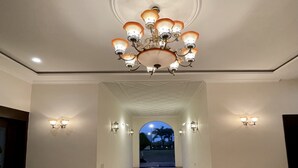 A hallway with a chandelier, wall sconces, and a marble floor. - BR Resort & Club (Sonkach)