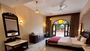 A hotel room with a bed, a desk, a dresser, and a large window with a view. - BR Resort & Club (Sonkach)