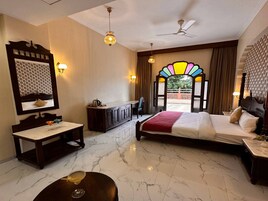 Quarto de hotel com cama, escrivaninha, penteadeira e uma janela grande com vista.