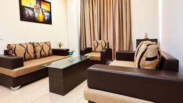 A modern living room with a sofa set, a glass coffee table, and a painting on the wall.