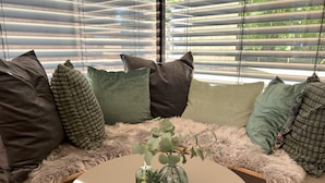 Un espace salon moderne avec une table ronde, de nombreux coussins et une petite plante en pot.
