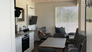 Une cuisine moderne avec des meubles blancs, un four encastré et un coin repas comprenant une table et des chaises.