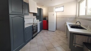 Eine Küche mit dunklen Schränken, einem roten Kühlschrank, einer weißen Spüle und einem Fenster, das für natürliches Licht sorgt.