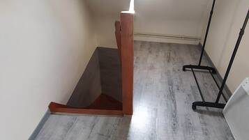 Ein Zimmer mit schrägem Dach, einem Stehpult und einer Deckenleuchte.