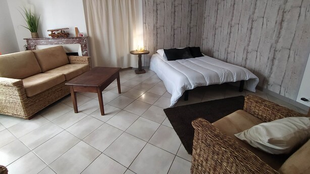 Ein modernes Schlafzimmer mit einem Bett, einem Sofa, einem Couchtisch und einem kleinen Tisch mit einer Lampe.