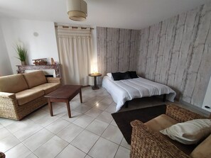 A modern bedroom with a bed, a sofa, a coffee table, and a small table with a lamp. - Petit nid Berrichon, Situé à Proximité du zoo de Beauval, Animaux Acceptés! (Écueillé)
