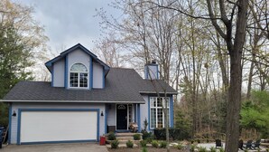 A two-story house with a garage, a front porch, and a landscaped yard. - Multi-week rental directly on Chandler Lake  deck, fire pit, tandem kayak. (Traverse City)