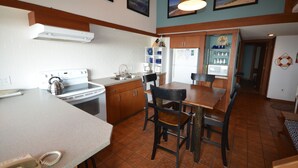 A kitchen with a stove, sink, and wooden cabinets. There is a dining area with a table and chairs.