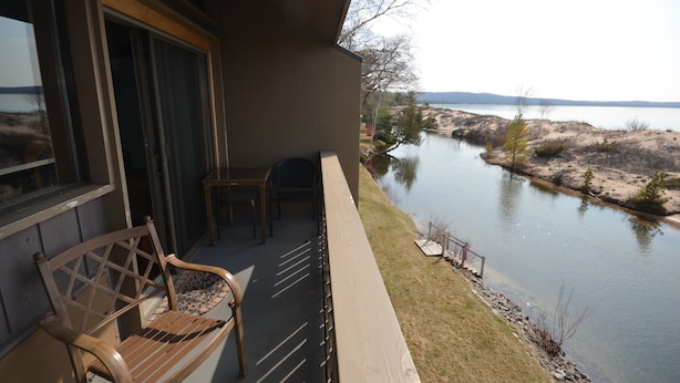 A balcony with a view of a lake, a wooden bench, and a small table.
