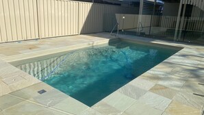 A rectangular swimming pool with clear water, surrounded by a tiled deck. - Renovated 3BR apartment with pool, WiFi, air-con & linen included, walking distance to beaches (Evans Head)