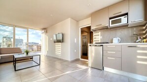 A modern kitchen with a built-in microwave, a coffee maker, and a dishwasher. There is a large window providing a view of the city. - Acropolis Magical View Suite @ Metro Kerameikos (Athens)
