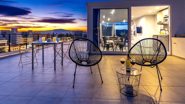 A rooftop terrace with two chairs and a table, a bottle of wine, and a glass. - Acropolis Magical View Suite @ Metro Kerameikos (Athens)