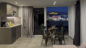 A modern apartment with a kitchen, dining area, and balcony with city views. - Acropolis Magical View Suite @ Metro Kerameikos (Athens)