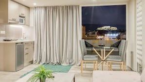 A modern kitchen with a built-in microwave, a dishwasher, and a dining area with a table and chairs. - Acropolis Magical View Suite @ Metro Kerameikos (Athens)