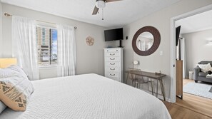 A bedroom with a bed, a dresser, a desk, a TV, and a mirror. - Sun, sand & serenity ~ The Good Life! (Gulf Shores)