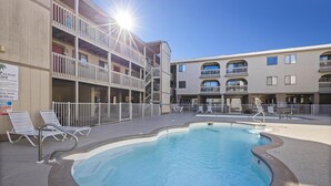 A pool area with lounge chairs and a sign indicating a guard duty schedule. - Sun, sand & serenity ~ The Good Life! (Gulf Shores)