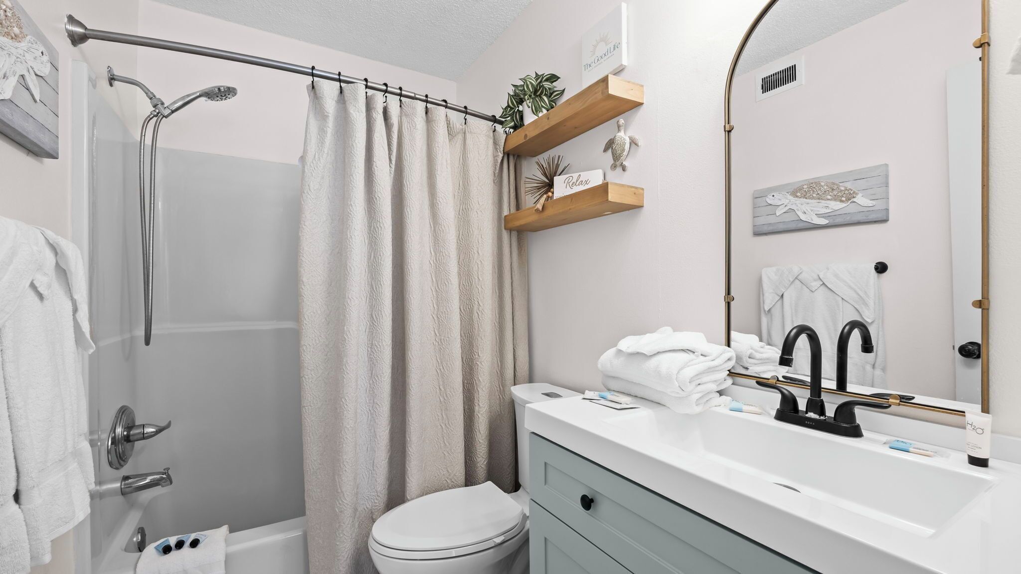 A bathroom with a shower, toilet, sink, and a mirror.