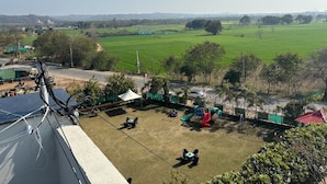 A playground with slides and swings, surrounded by green fields and trees. - Siswan View Hotel (Kharar)
