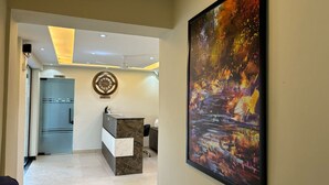 A modern reception area with a marble counter, a clock, and a large abstract painting. - Siswan View Hotel (Kharar)