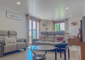 A living room with a sofa, a coffee table, and a dining area with a table and chairs.
