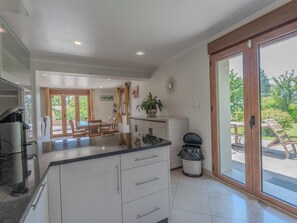 A modern kitchen with a dining area, a trash bin, and a sliding glass door leading to an outdoor patio.