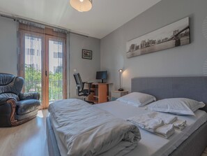 Une chambre d’hôtel avec un lit, un bureau, une chaise et un tableau représentant un paysage urbain.