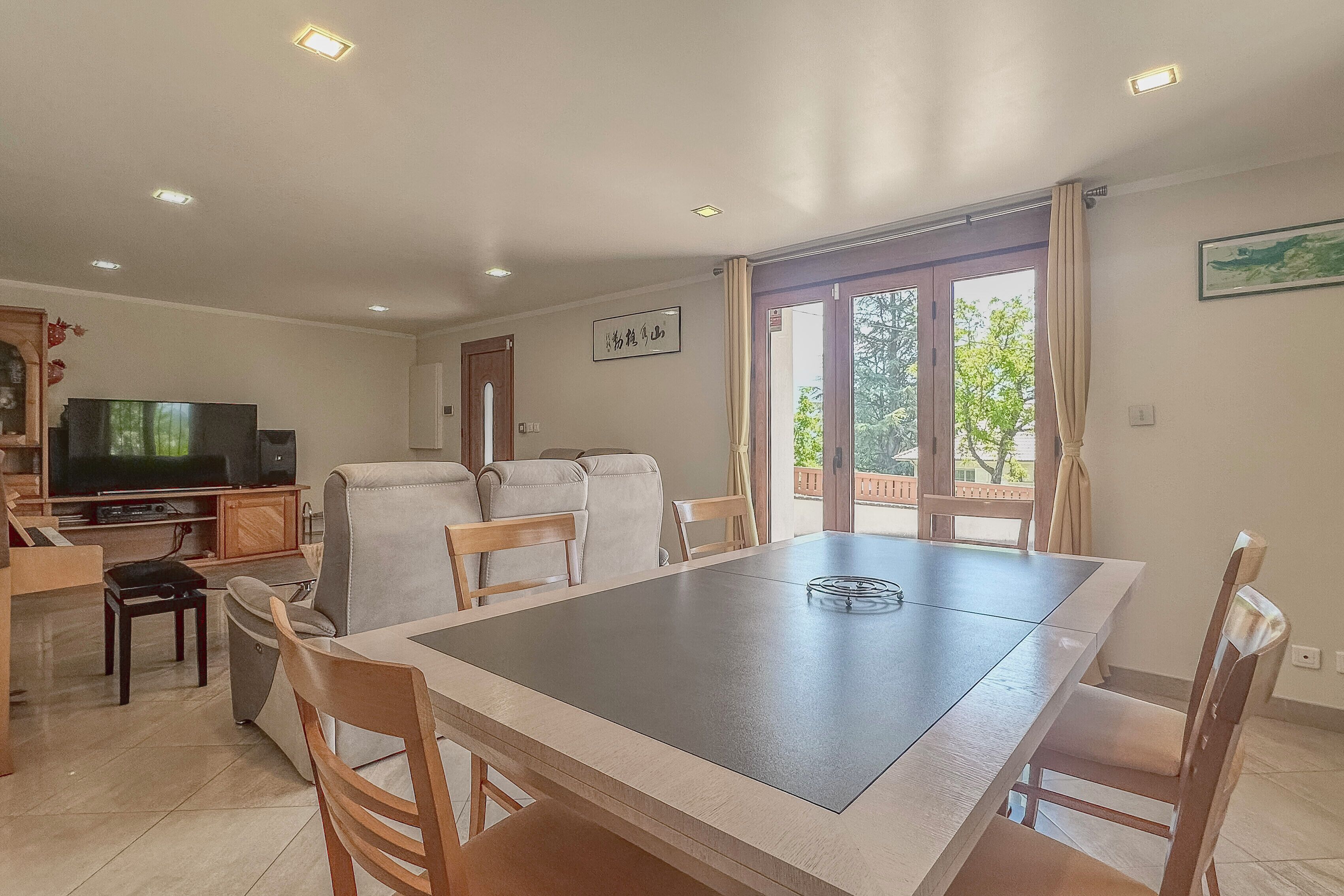 Un espace repas comprenant une table et des chaises, un téléviseur et une vue sur l’extérieur.