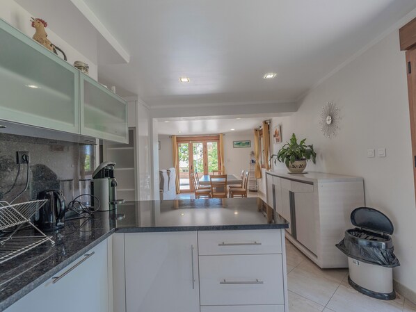 Una cocina moderna con una isla central, un comedor con mesa y sillas, y vistas a un patio.