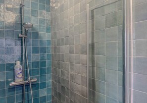 A shower area with blue tiles and a handheld showerhead.