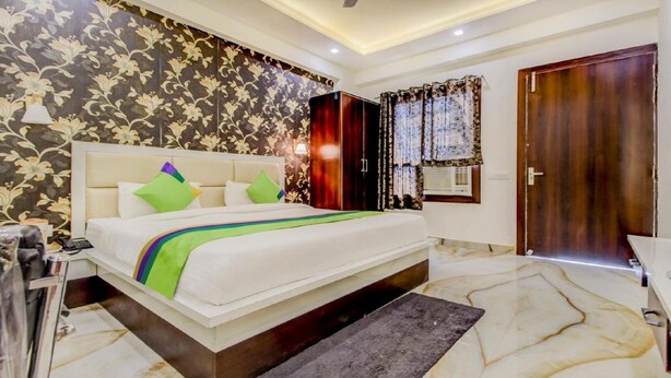 A bedroom with a bed, a nightstand, a wardrobe, and a bathroom. - Hotel Vedic Inn (Kiraoli)