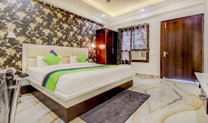 A bedroom with a bed, a nightstand, a wardrobe, and a bathroom. - Hotel Vedic Inn (Kiraoli)