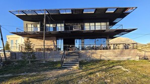 Un edificio moderno con tetto piatto, ampie finestre e una scala che conduce a un piano superiore.
