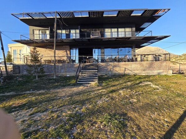 A modern building with a flat roof, large windows, and a staircase leading to an upper level. - Wiyana Wanda (Elmali)
