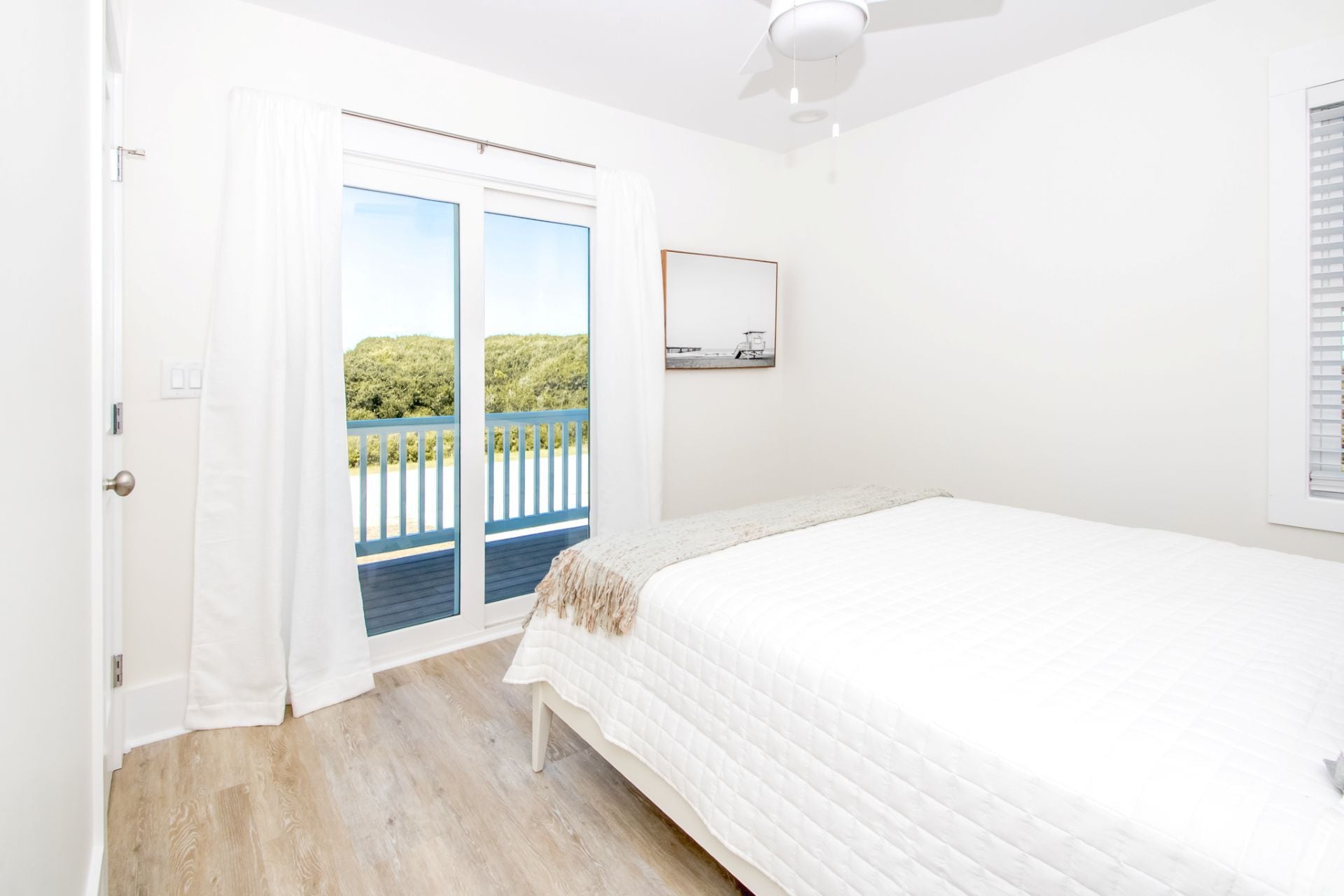 Un dormitorio con cama, puerta que da a un balcón y ventilador de techo.