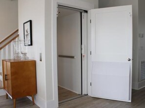 Un couloir avec une armoire en bois, une porte blanche et un tableau encadré accroché au mur.