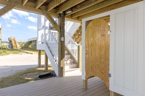 Une terrasse en bois avec un escalier menant à une porte blanche.